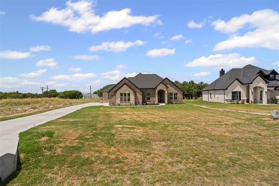 French provincial home with stone siding, a front yard, a chimney, and driveway French provincial home with stone siding, a front yard, a chimney, and driveway