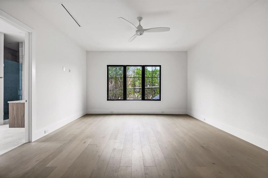 Spare room featuring light wood-type flooring, ceiling fan, and baseboards