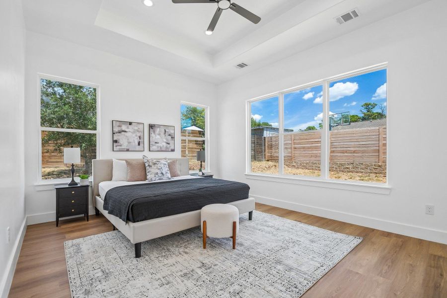 Crisp white walls and warm wood flooring frame a spacious bedroom featuring a recessed ceiling. Crisp white walls and warm wood flooring frame a spacious bedroom featuring a recessed ceiling.