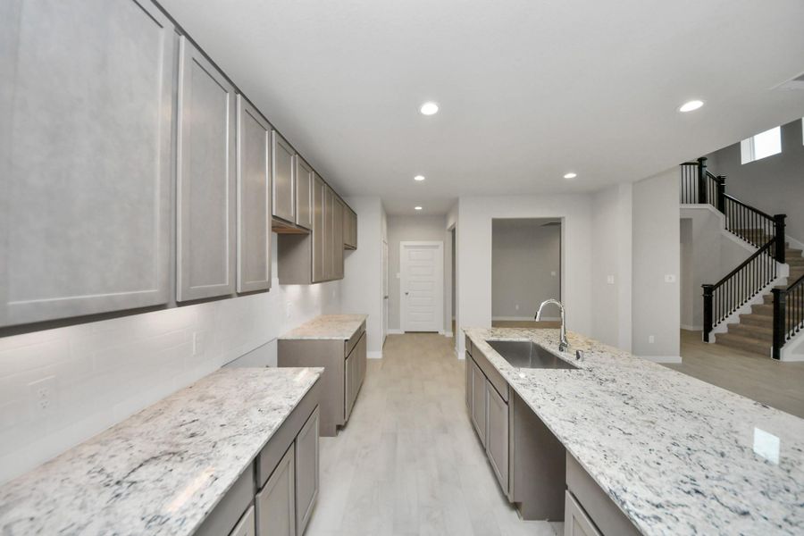 Culinary haven, featuring granite countertops, a tile backsplash, stainless steelappliances (to be installed), and 42” upper cabinets. Sample photo of completed home with similar floor plan. Actual colors and selections may vary. Culinary haven, featuring granite countertops, a tile backsplash, stainless steelappliances (to be installed), and 42” upper cabinets. Sample photo of completed home with similar floor plan. Actual colors and selections may vary.