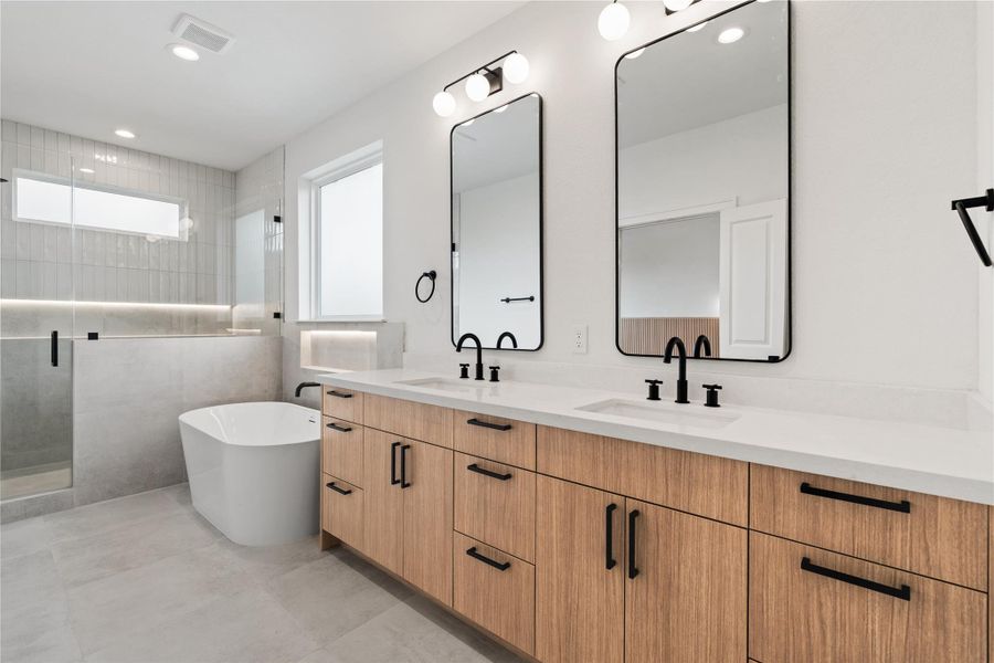 Spa-like primary bath featuring a double vanity, soaking tub, and oversized walk-in shower.