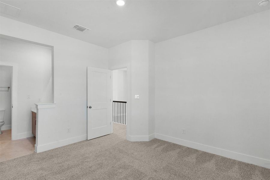 A well-lit area providing versatile space, featuring a connection to a private bathroom and access to a hallway.