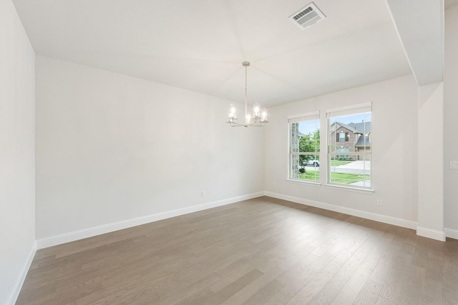 Empty dining room with hardwood floors, chandelier, and large window with neighborhood view Empty dining room with hardwood floors, chandelier, and large window with neighborhood view