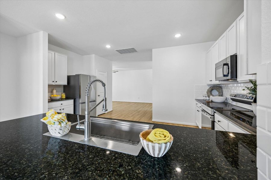 Kitchen featuring backsplash, white cabinets, dark stone countertops, stainless steel appliances, and light wood finished floors