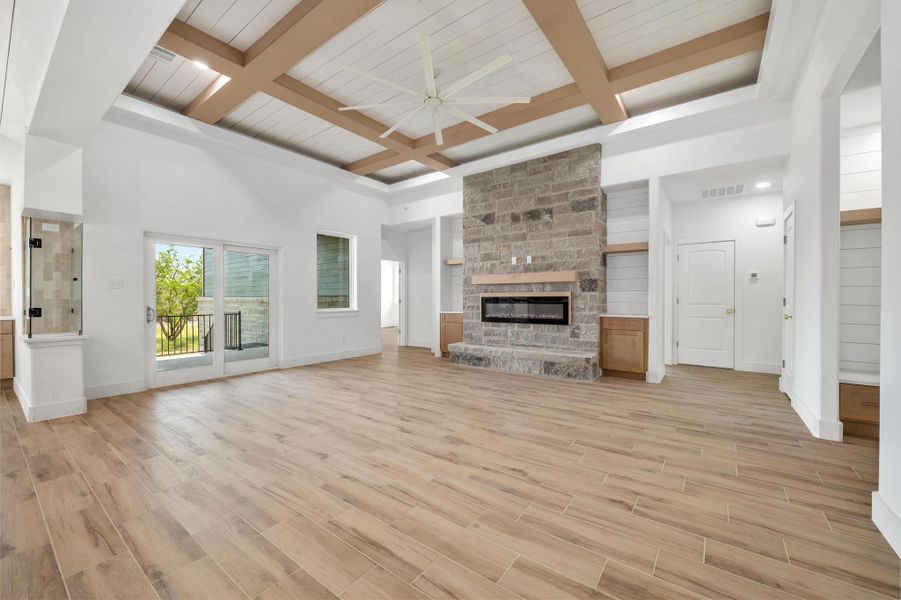 Living room with light wood-style flooring, beam ceiling, coffered ceiling, a fireplace, and ceiling fan Living room with light wood-style flooring, beam ceiling, coffered ceiling, a fireplace, and ceiling fan