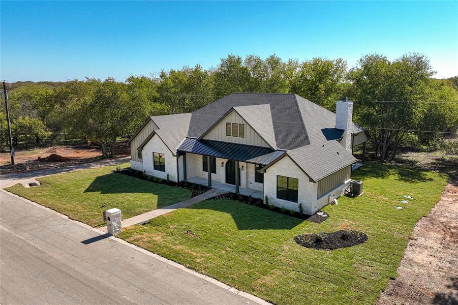 Modern farmhouse with a standing seam roof, a metal roof, a porch, a front lawn, and a shingled roof