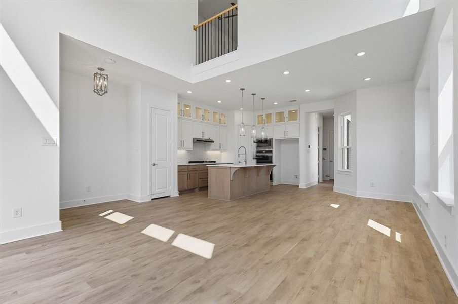 Kitchen featuring a breakfast bar area, glass insert cabinets, open floor plan, recessed lighting, and a kitchen island with sink Kitchen featuring a breakfast bar area, glass insert cabinets, open floor plan, recessed lighting, and a kitchen island with sink