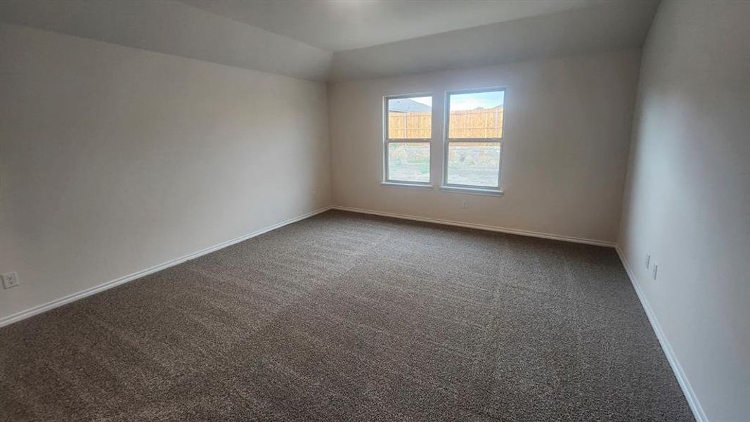 Spacious room featuring neutral carpeting, light-toned walls, and a tray ceiling