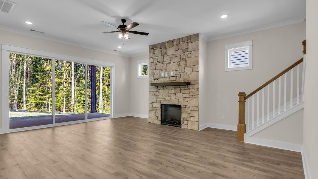 Living room with central fireplace and large rear windows (Representative of completed home)