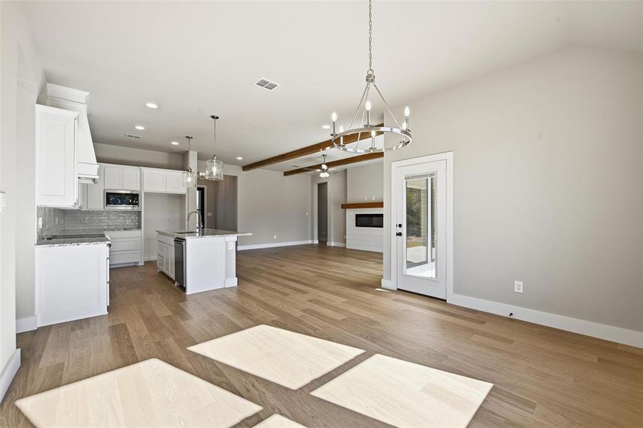 Kitchen featuring white cabinetry, open floor plan, hanging light fixtures, a chandelier, and decorative backsplash Kitchen featuring white cabinetry, open floor plan, hanging light fixtures, a chandelier, and decorative backsplash