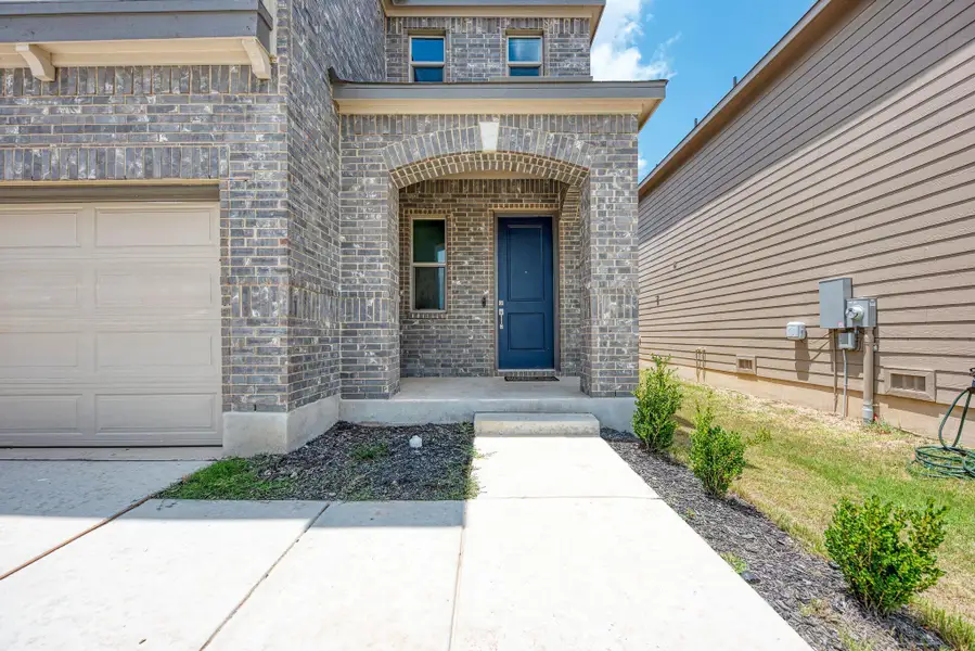 A welcoming arched entryway and attached garage define this modern brick and siding home.