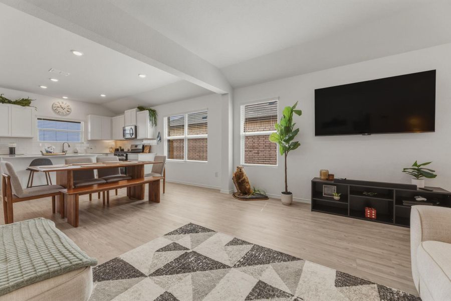 Expansive open-concept living area featuring light-toned flooring, recessed lighting, and large windows providing natural light