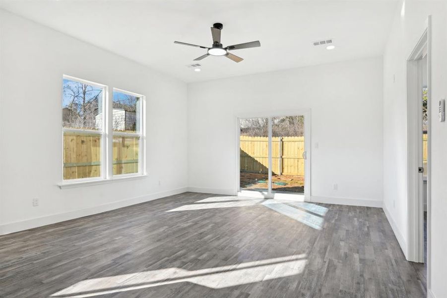 Empty room featuring a ceiling fan, visible vents, baseboards, and wood finished floors