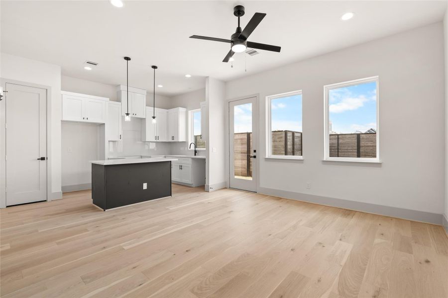 The main level opens up — engineered wood floors, white kitchen, and backyard right there The main level opens up — engineered wood floors, white kitchen, and backyard right there