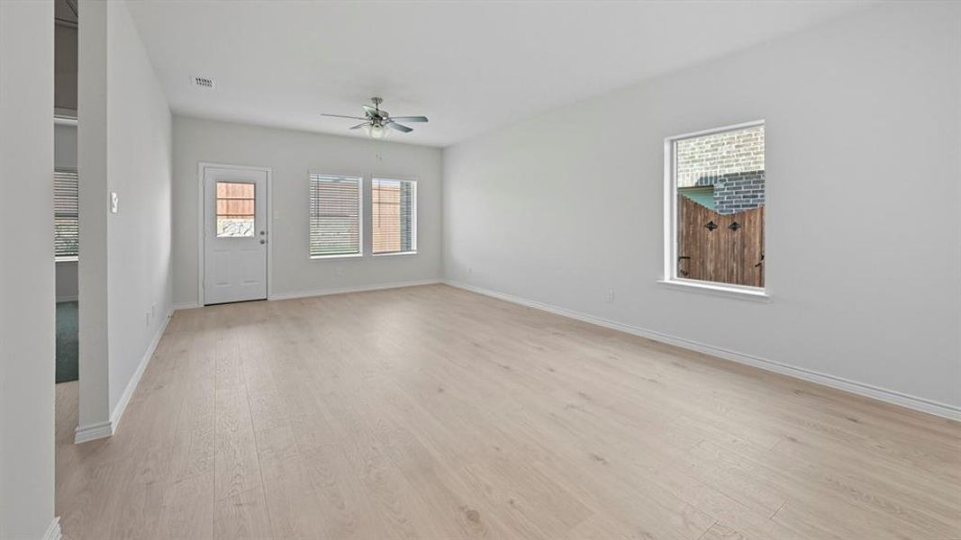 Unfurnished room featuring light wood-type flooring, healthy amount of natural light, and a ceiling fan