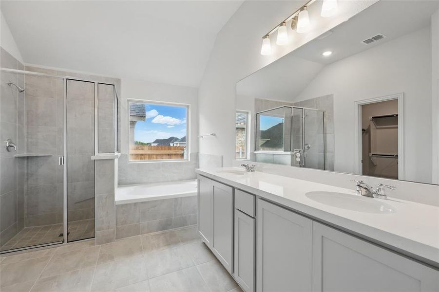 Full bath with vaulted ceiling, a shower stall, double vanity, a bath, and tile patterned flooring Full bath with vaulted ceiling, a shower stall, double vanity, a bath, and tile patterned flooring