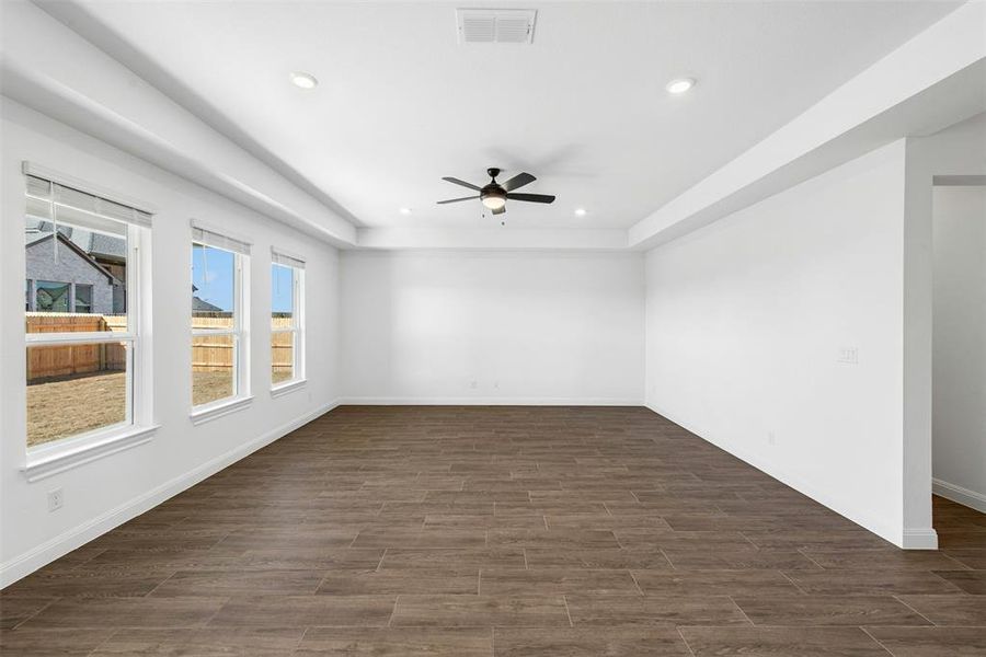 Spacious room featuring wood-finish flooring, white walls, and a recessed ceiling with integrated lighting