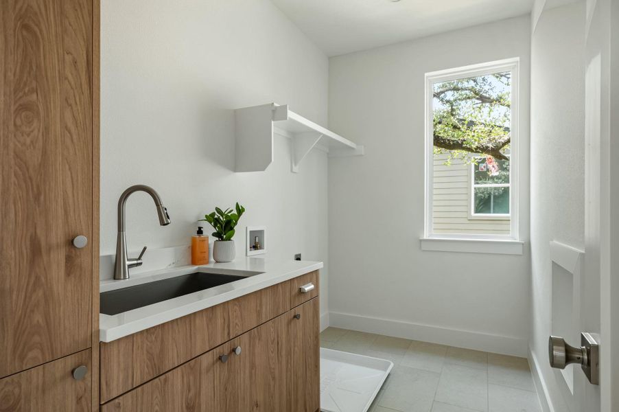 A well-appointed laundry room features a deep basin sink, custom cabinetry, and natural light. A well-appointed laundry room features a deep basin sink, custom cabinetry, and natural light.