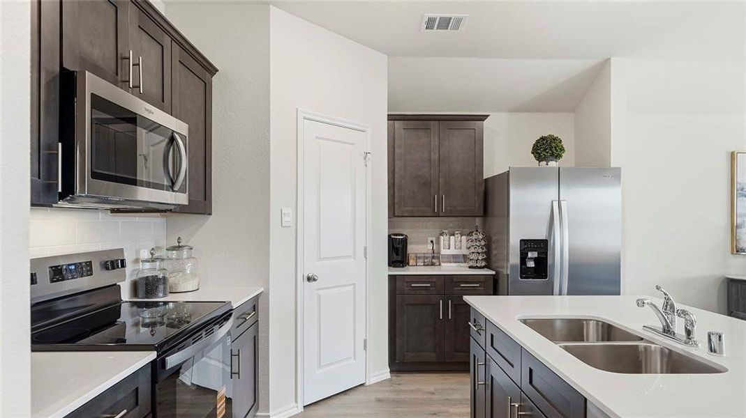 Kitchen featuring stainless steel appliances, dark wood finish cabinets, and decorative backsplash