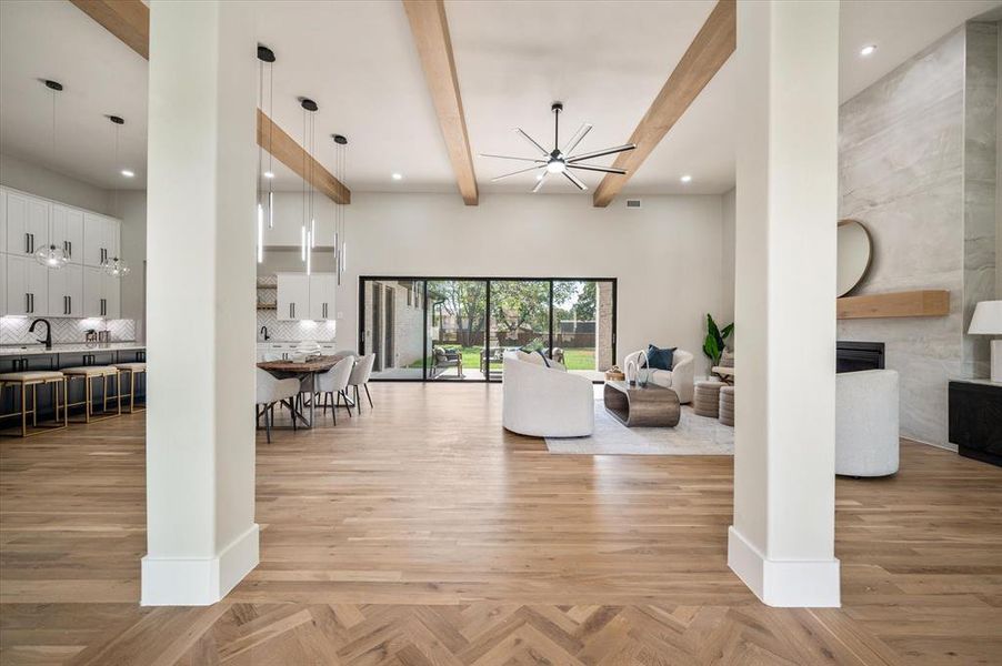 Living room featuring a high ceiling, a notable chandelier, sink, light parquet floors, and beam ceiling