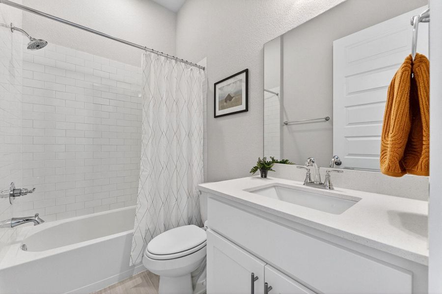 Secondary bathroom suite in the bedroom downstairs, featuring shower/tub combo.