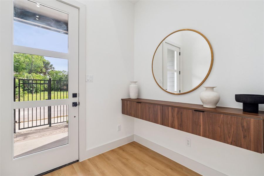 Transom-style glass panels and floating cabinetry create an airy, light-filled entry that feels both grounded and effortlessly stunning.