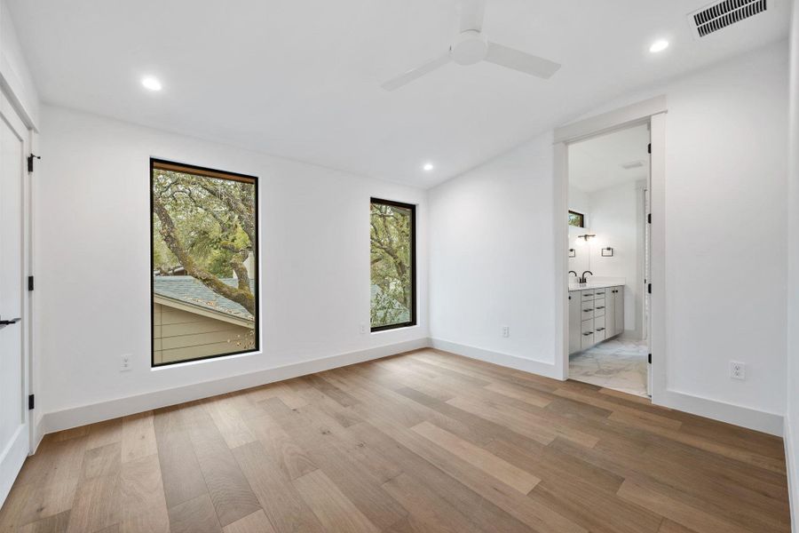 Unfurnished bedroom with a ceiling fan, light wood-type flooring, connected bathroom, and recessed lighting