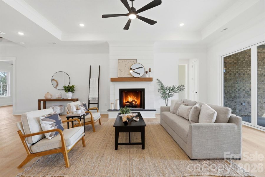 living room w/ ventless gas fireplace, tray ceiling, and 8ft sliding glass doors to the covered rear patio