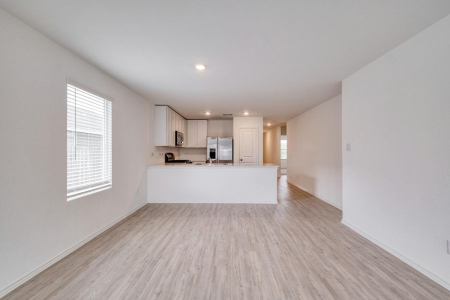 Open-concept living area featuring wood-finish flooring, white walls, and recessed lighting