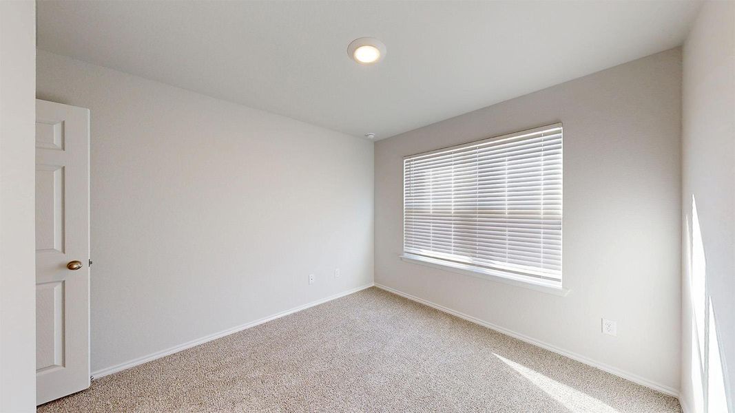 Neutral-toned room featuring a window with horizontal blinds, recessed ceiling lighting, and light-colored carpeting