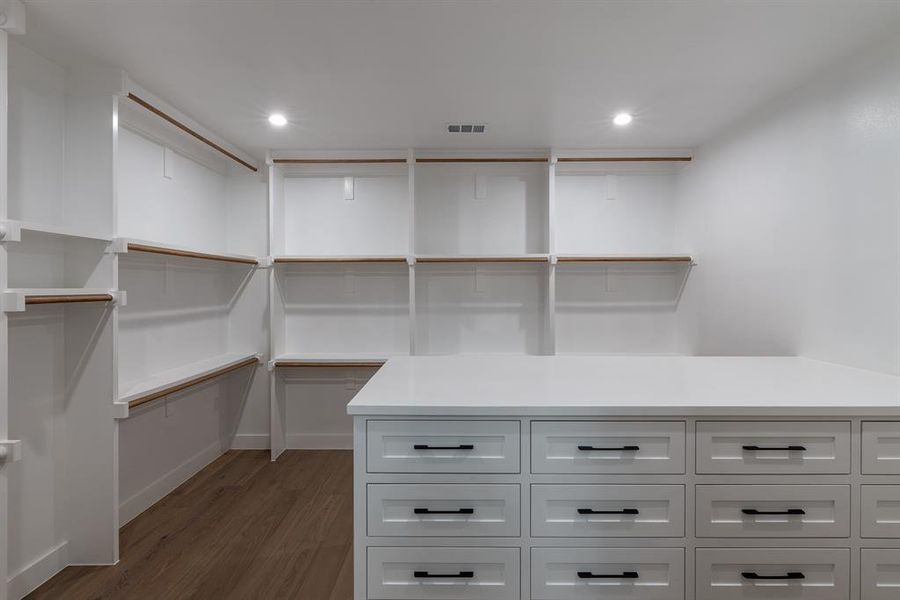 Spacious closet featuring white oak flooring and custom dresser.