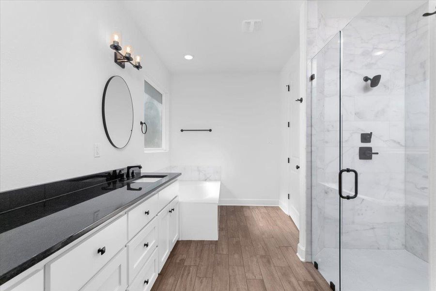 Bathroom with vanity, a marble finish shower, wood finished floors, a tub, and baseboards Bathroom with vanity, a marble finish shower, wood finished floors, a tub, and baseboards