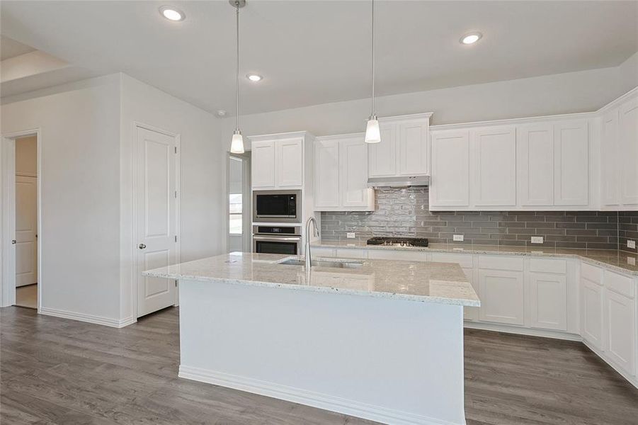 Kitchen with appliances with stainless steel finishes, an island with sink, and white cabinets