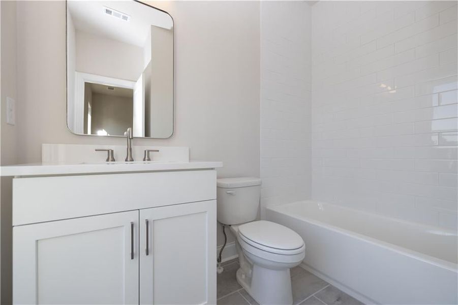 Bathroom featuring vanity, shower / tub combination, and light tile patterned flooring