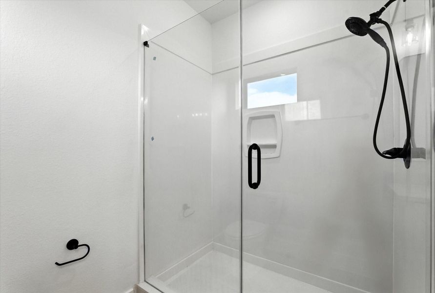Enjoy a walk-in shower featuring a built-in soap niche, a modern showerhead with handheld attachment, all beautifully enclosed in sleek glass.