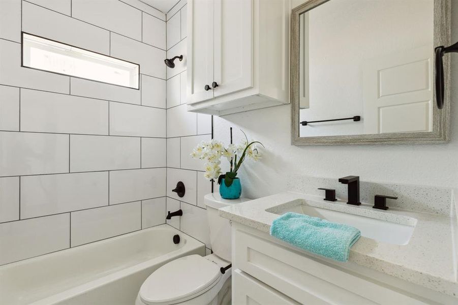 Full bathroom with tiled shower / bath combo, toilet, and vanity