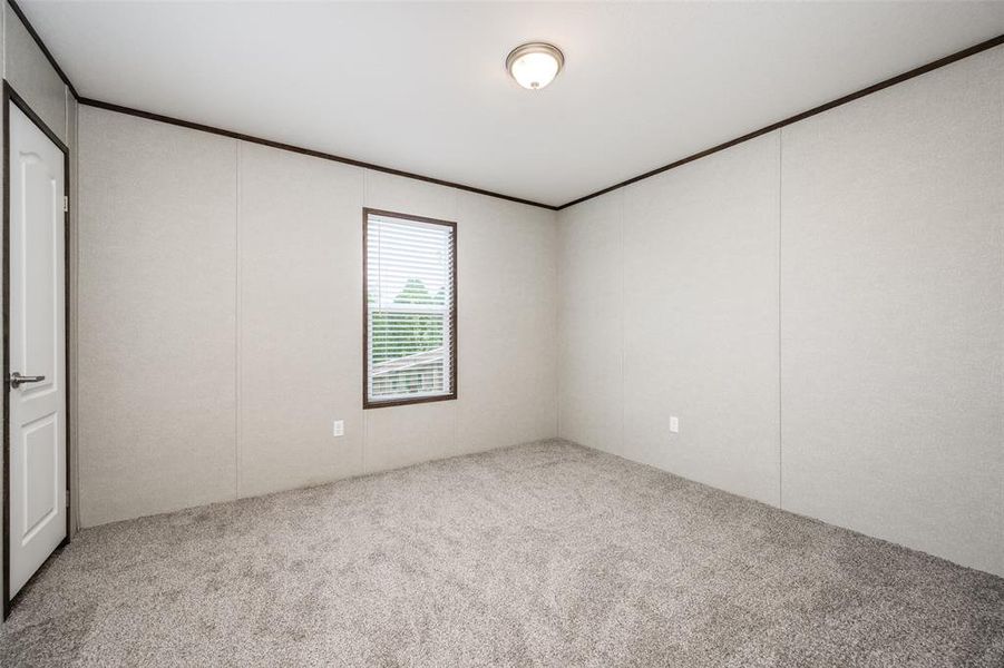 Unfurnished bedroom featuring light carpet, ornamental molding, and a decorative wall Unfurnished bedroom featuring light carpet, ornamental molding, and a decorative wall