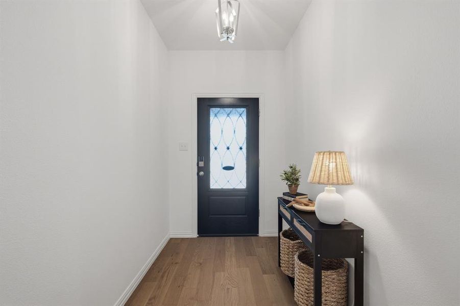 Welcoming entry with beautiful front door, wide hallway, and beautiful real wood flooring. The first impression feels bright, clean, and move-in ready.