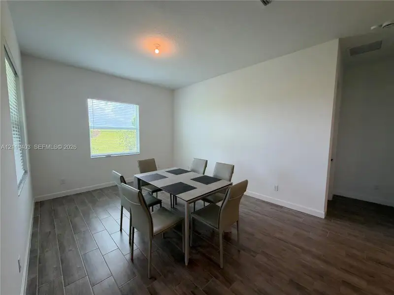 Room featuring neutral wall paint, wood-finish tile flooring, and dual windows with horizontal blinds