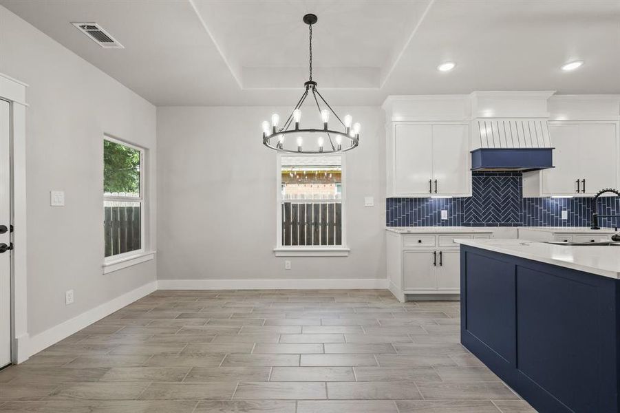 Kitchen featuring a chandelier, light countertops, wood tiled floors, tasteful backsplash, and recessed lighting