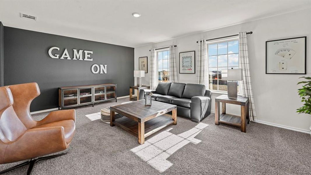 Spacious living area featuring carpet flooring, large windows with natural light, and a dark accent wall Spacious living area featuring carpet flooring, large windows with natural light, and a dark accent wall