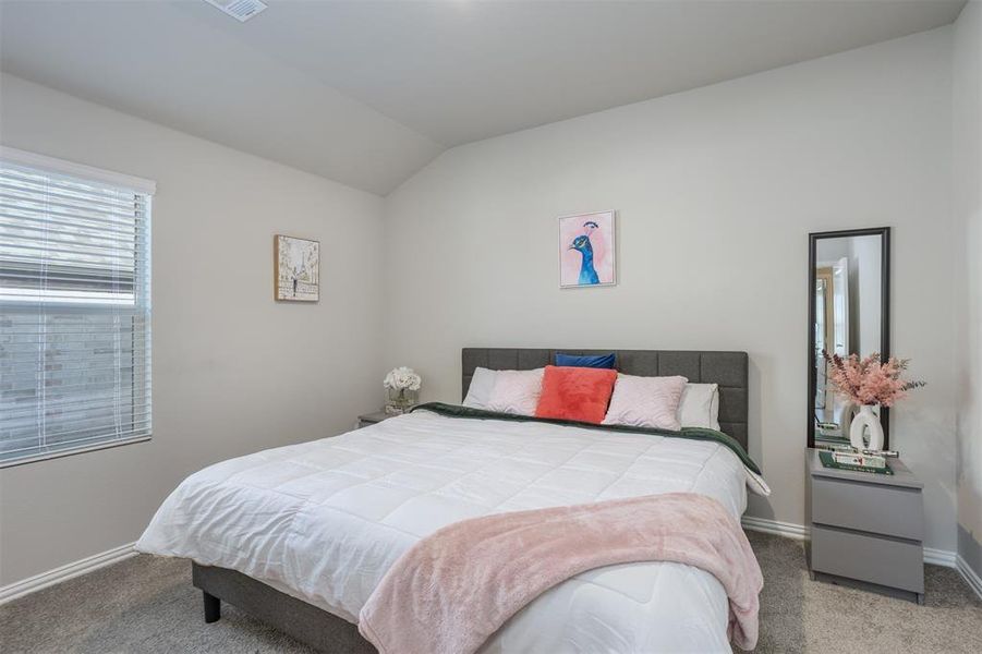 Carpeted bedroom featuring vaulted ceiling and baseboards Carpeted bedroom featuring vaulted ceiling and baseboards