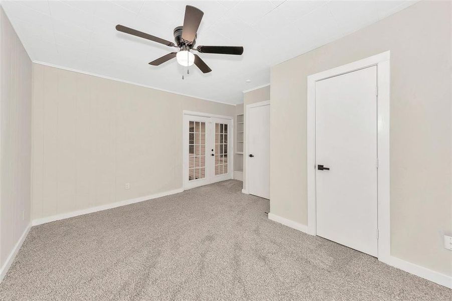 Carpeted spare room featuring french doors, a ceiling fan, and ornamental molding Carpeted spare room featuring french doors, a ceiling fan, and ornamental molding