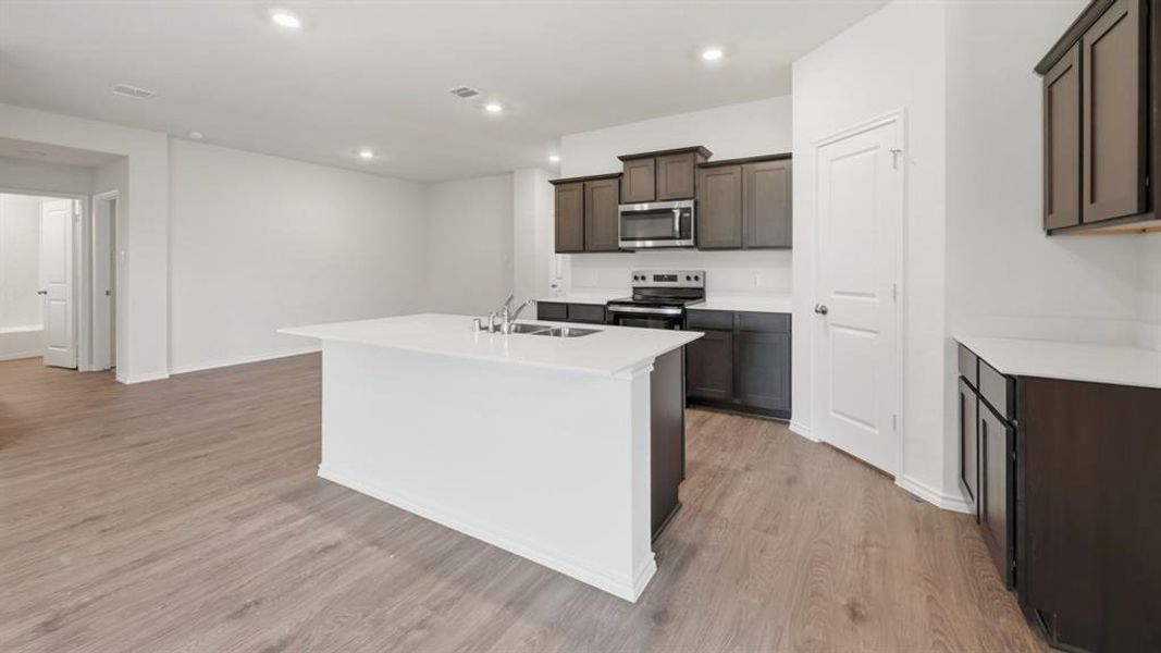 Kitchen with an island with sink, stainless steel appliances, light wood-style flooring, light stone countertops, and recessed lighting Kitchen with an island with sink, stainless steel appliances, light wood-style flooring, light stone countertops, and recessed lighting