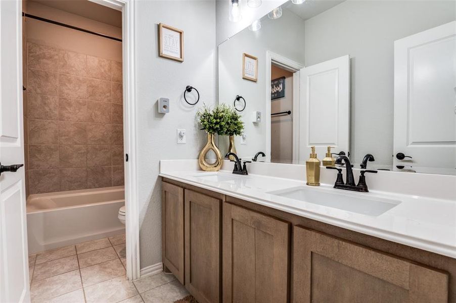 Full bath featuring double vanity, tile patterned floors, and shower / bathtub combination Full bath featuring double vanity, tile patterned floors, and shower / bathtub combination
