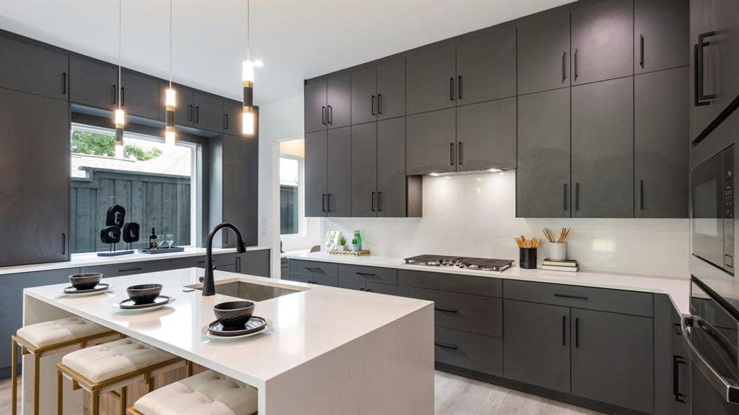 Kitchen featuring a center island with sink, decorative light fixtures, light wood-type flooring, sink, and a breakfast bar