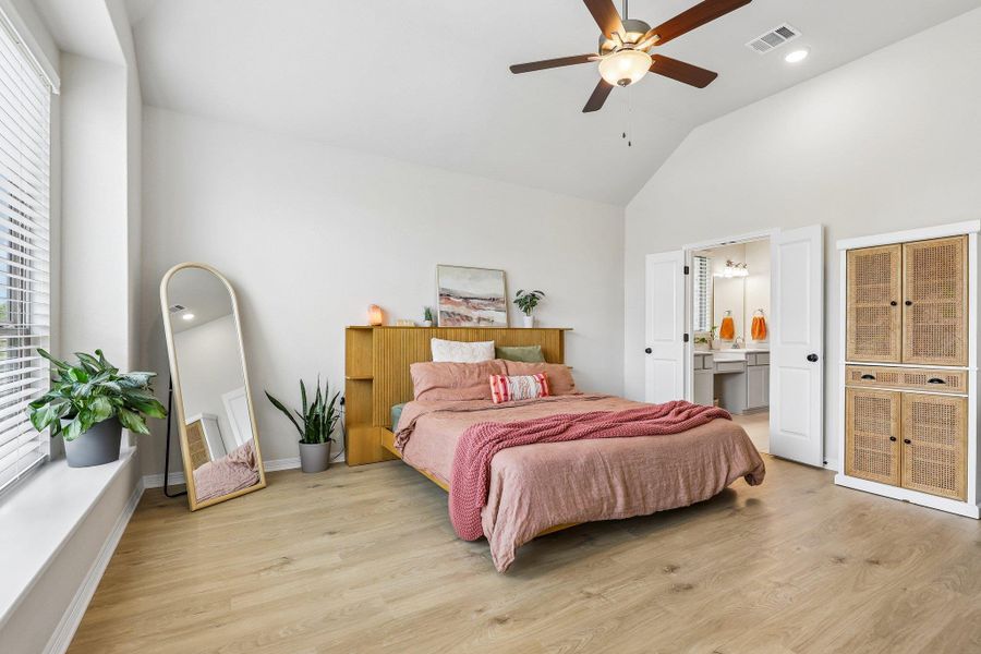 Lofty ceilings and light hardwood floors characterize this inviting bedroom retreat, offering ample space and direct bathroom access.