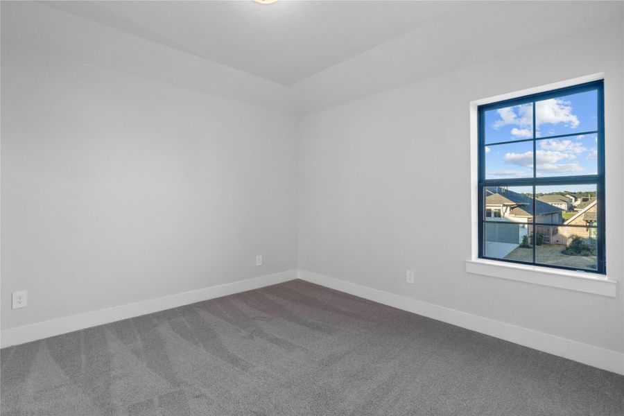 This secondary bedroom shares a jack-n-jill secondary bathroom with another bedroom. it features neutral-toned wall, plush carpet flooring, walk-in closet, and a large window.