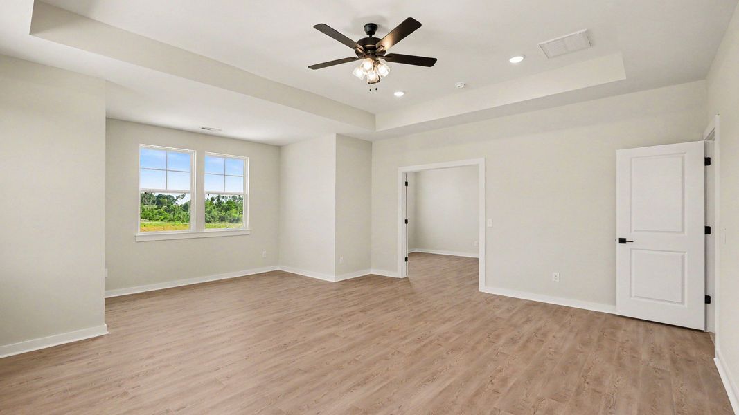 Second Floor primary bedroom with hardwood flooring, tray ceiling, and view of connected private study
