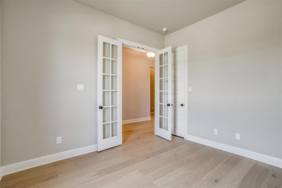 Unfurnished bedroom with light hardwood / wood-style floors and french doors